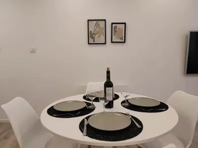 a white dining room table with a bottle of wine at Le Jardin Secret ConciergerieDameCarcas in Carcassonne