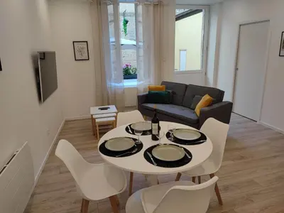 a living room with a table and chairs and a couch at Le Jardin Secret ConciergerieDameCarcas in Carcassonne