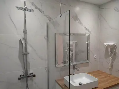 a bathroom with a glass shower and a sink at Le Jardin Secret ConciergerieDameCarcas in Carcassonne