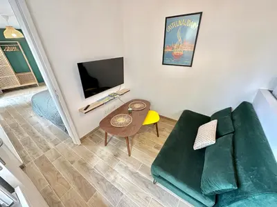 a living room with a green couch and a tv at Evasion dépaysante Canal du Midi* Jardin &Terrasse in Castelnaudary