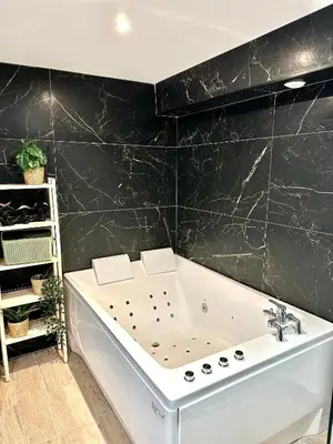 a bath tub in a bathroom with a black wall at Evasion dépaysante Canal du Midi * Terrasse & SPA in Castelnaudary