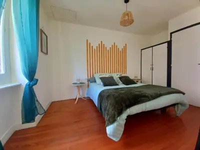 a bedroom with a large bed and a blue curtain at Charmant T2 indépendant in Belcaire