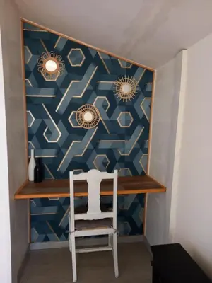 a table and a chair in front of a blue wall at Charmant T2 indépendant in Belcaire
